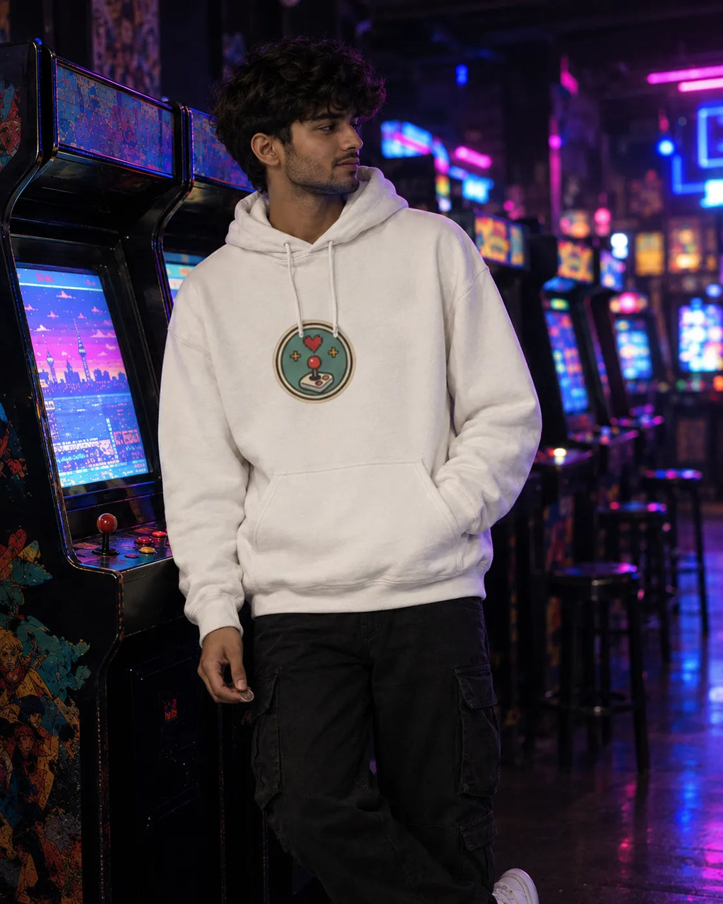 Man leaning against an arcade machine in a neon-lit arcade, wearing an off-white One More Round Korean hoodie with a small round front chest print