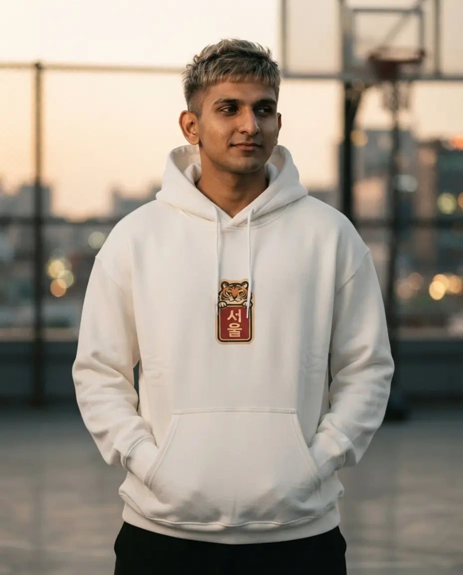 Man on an outdoor basketball court at sunset, wearing an off-white Tiger Mode On Korean hoodie with a small front chest print