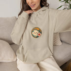 Woman sitting on a sofa in a beige hoodie with a round chest print