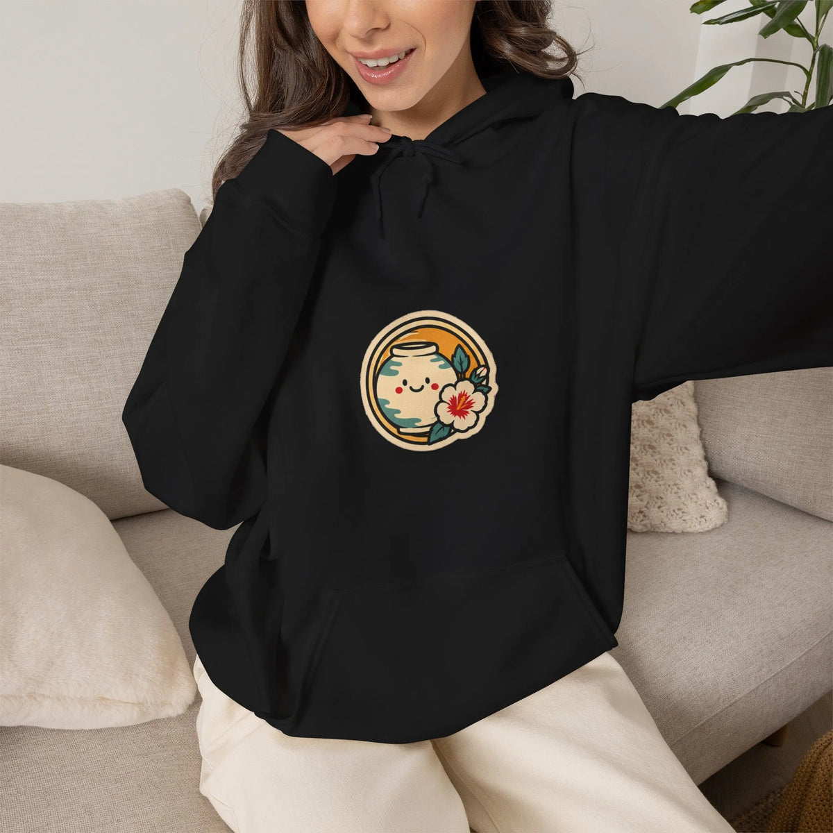 Woman relaxing on a sofa in a black hoodie with a round chest print