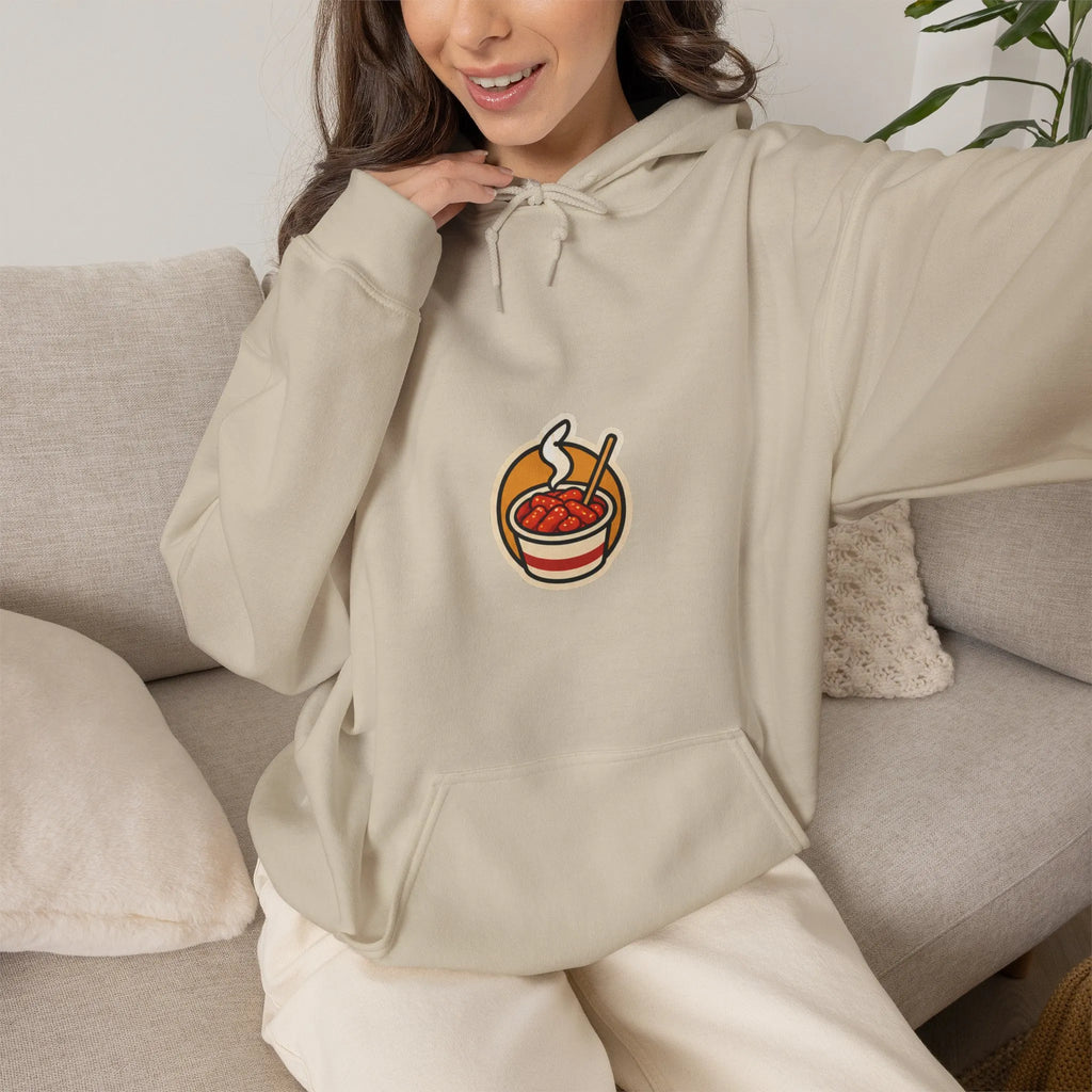 Woman sitting on a sofa in a beige hoodie with a small tteokbokki print
