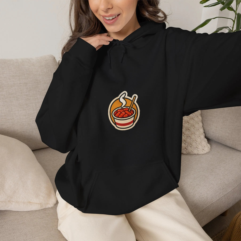 Woman on a sofa in a black hoodie with a small tteokbokki cup print on the chest
