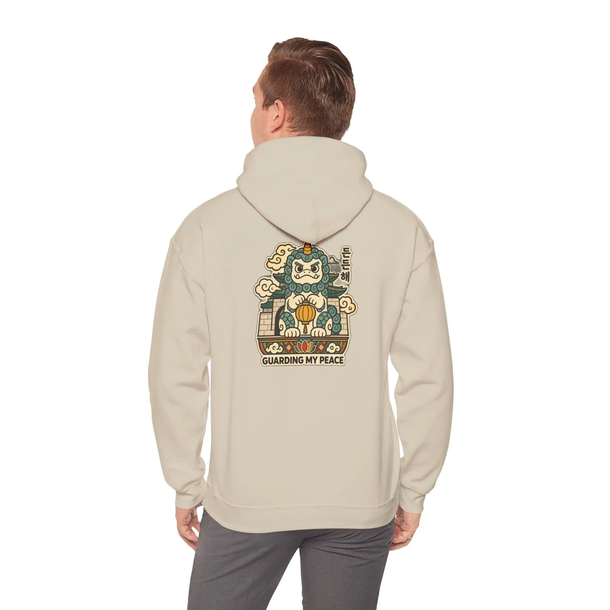 Back view of a beige hoodie with a haetae guardian print, worn by a man