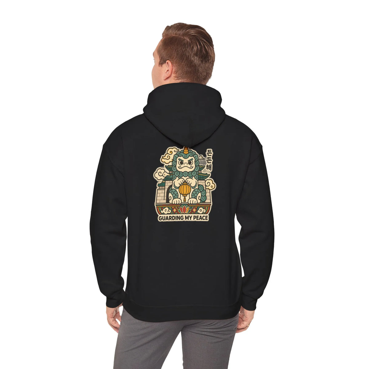 Back view of a black hoodie with a haetae guardian print, worn by a man