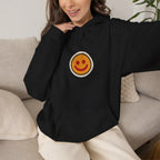Woman sitting on a sofa in a black hoodie with a small smiley face print