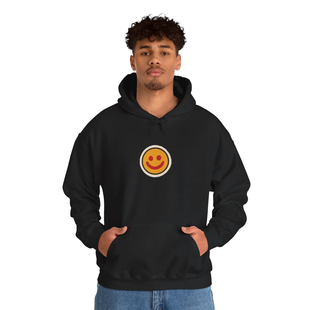 Man in a black hoodie with a small smiley face print on the chest