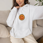 Woman relaxing on a sofa in an off-white hoodie with a small smiley face print