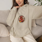 Woman relaxing on a sofa in a beige hoodie with a small lucky pouch badge