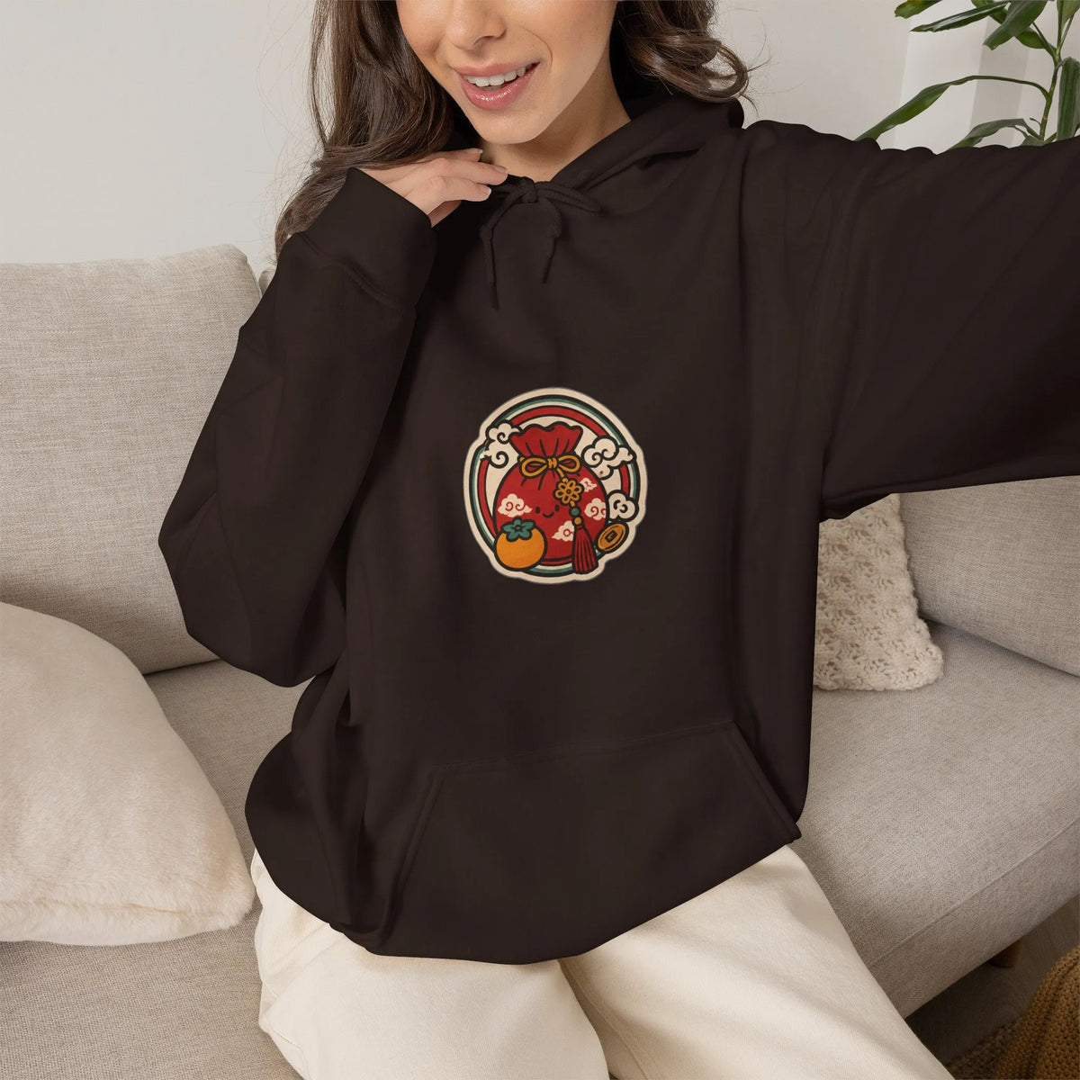 Woman on a sofa in a coffee brown hoodie with a small lucky pouch badge