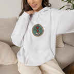 Woman relaxing on a sofa in an off-white hoodie with a small round gaming badge