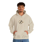 Man wearing a beige hoodie with a small round athletic badge on the chest