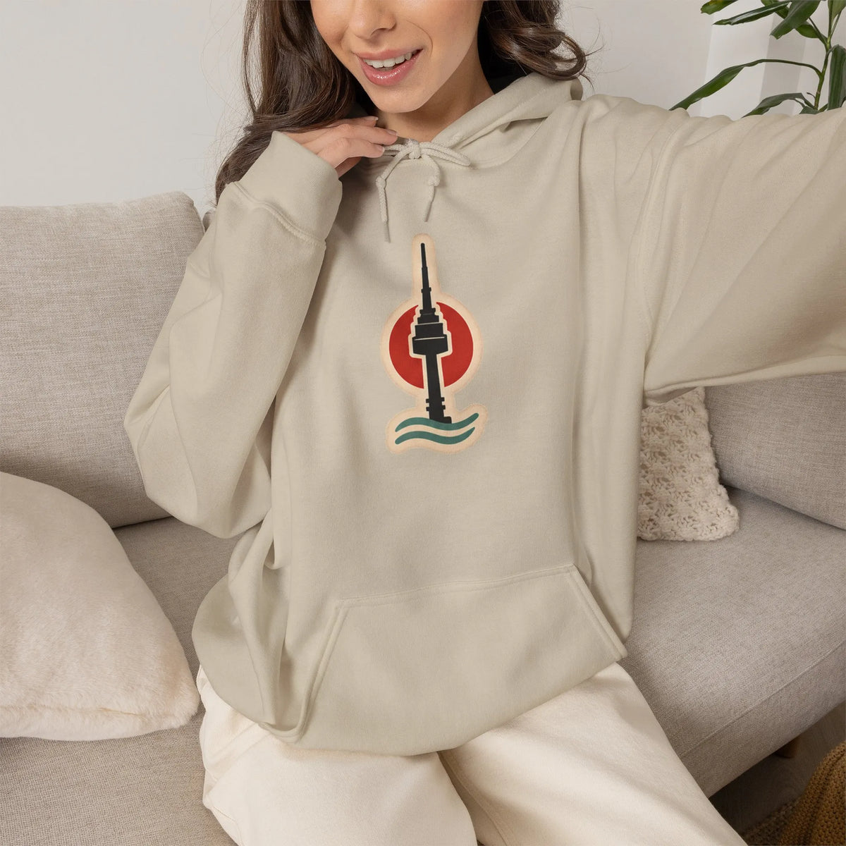 Woman relaxing on a sofa in a beige hoodie with a small Seoul print