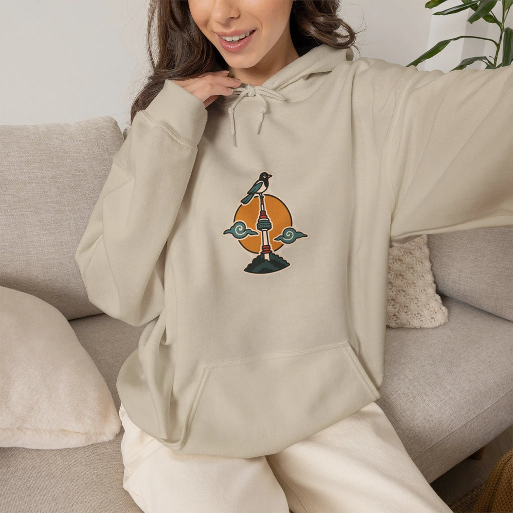 Woman on a sofa in a beige hoodie with a small N Seoul Tower print