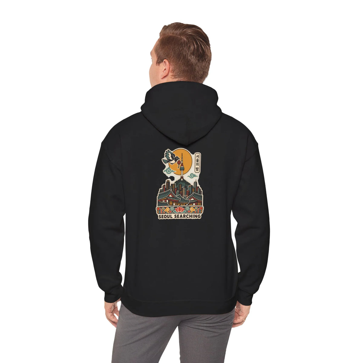 Back view of a black hoodie with a Seoul night skyline print, worn by a man