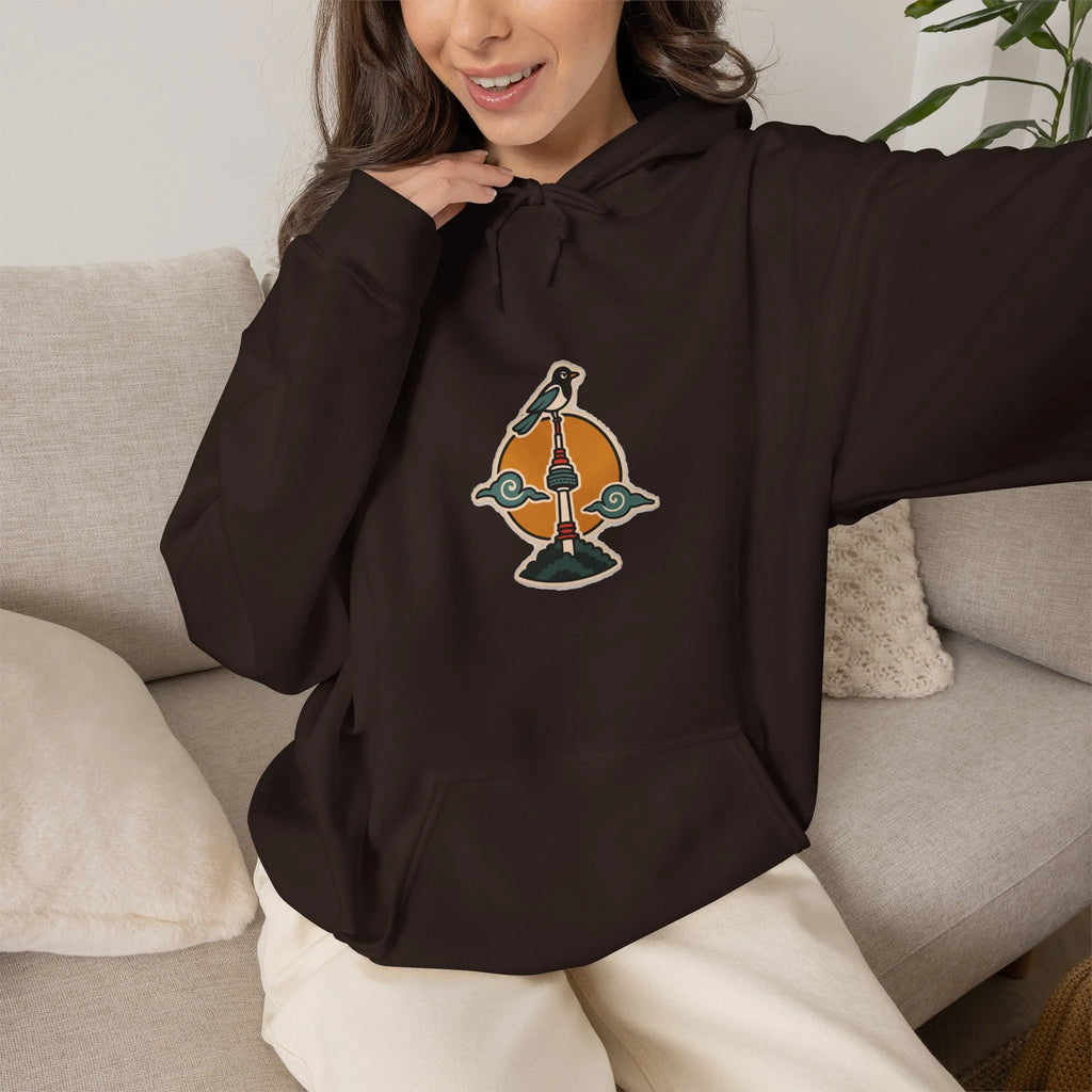 Woman on a sofa in a coffee brown hoodie with a small N Seoul Tower print