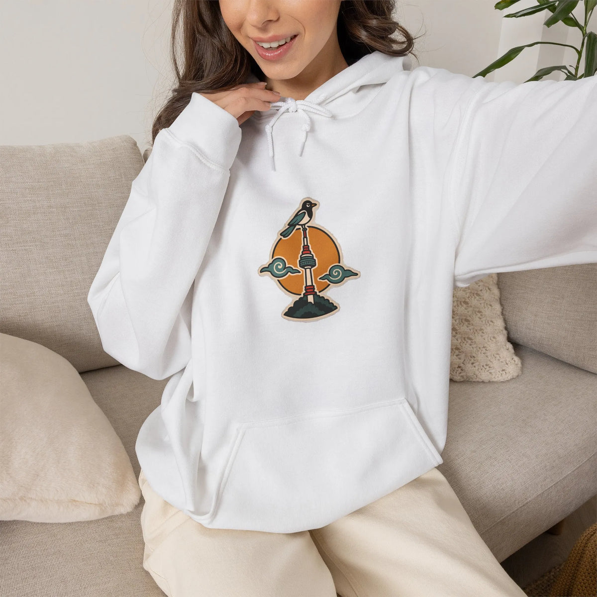 Woman relaxing on a sofa in an off-white hoodie with a small N Seoul Tower print