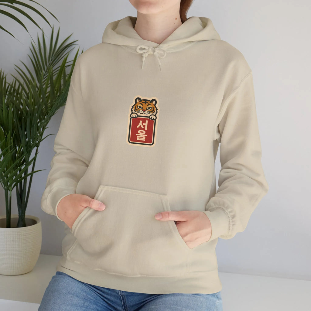 Woman standing at home in a beige hoodie with hands in the pocket